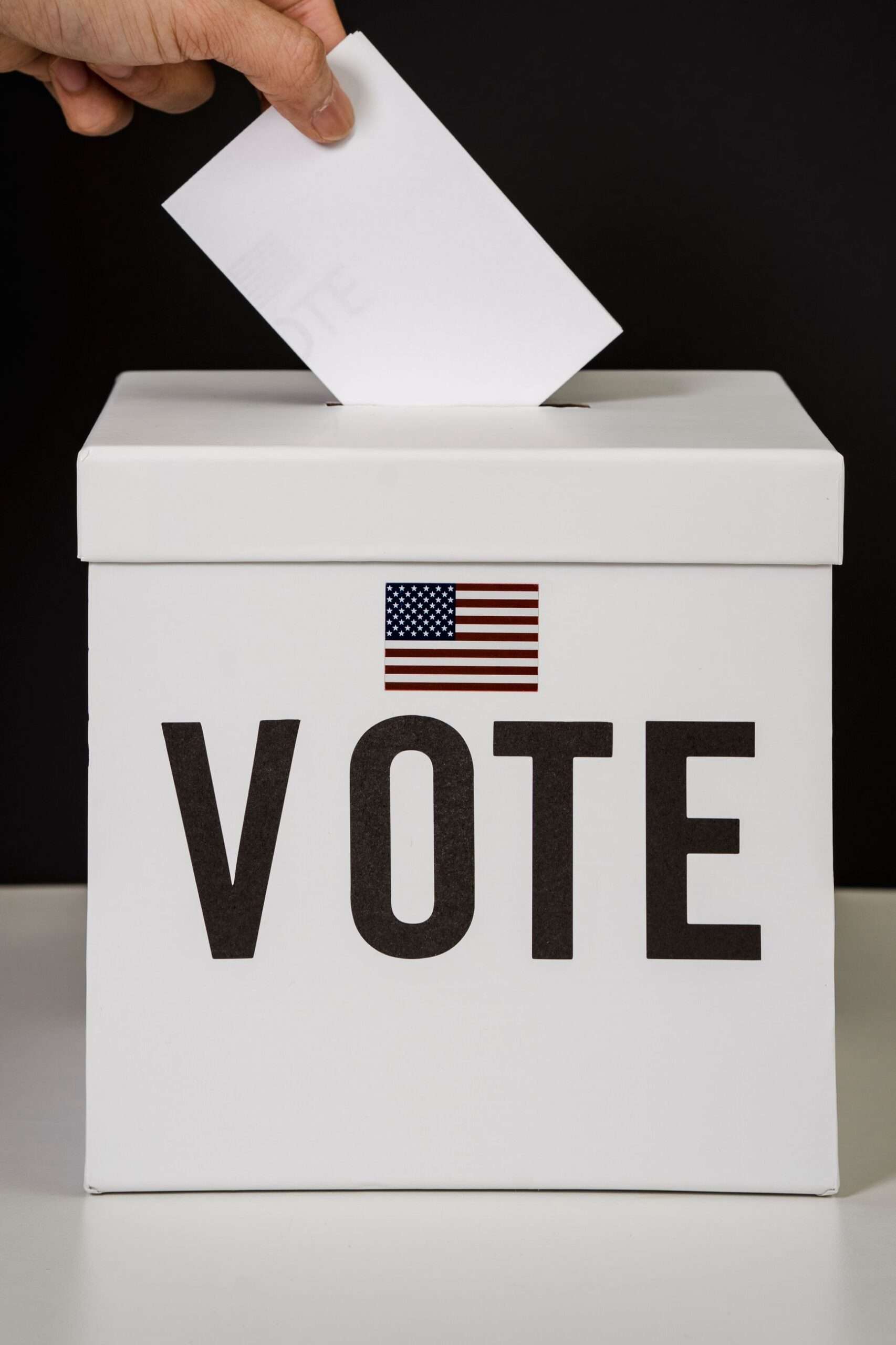 A person placing a paper ballot into a voting box
