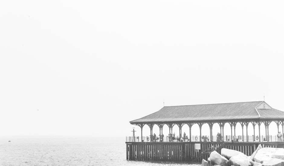 A wooden pier extends over calm bay waters