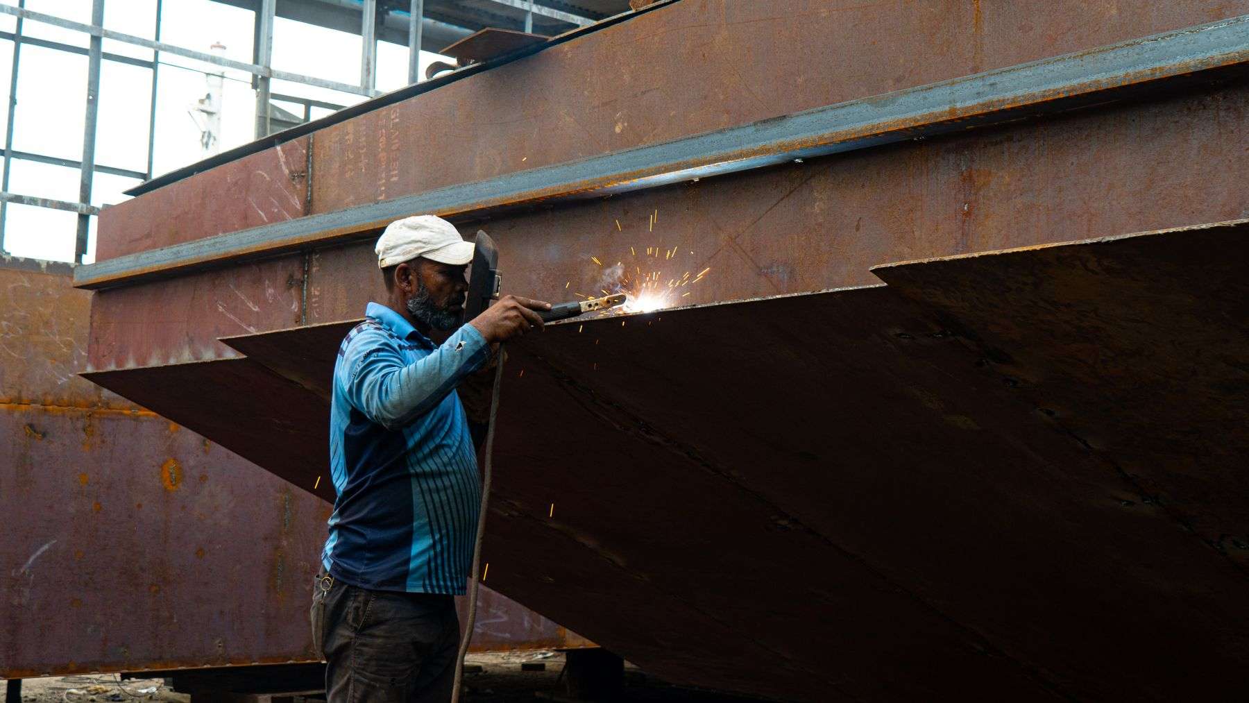 A welder works on a large metal structure during hands-on welding training