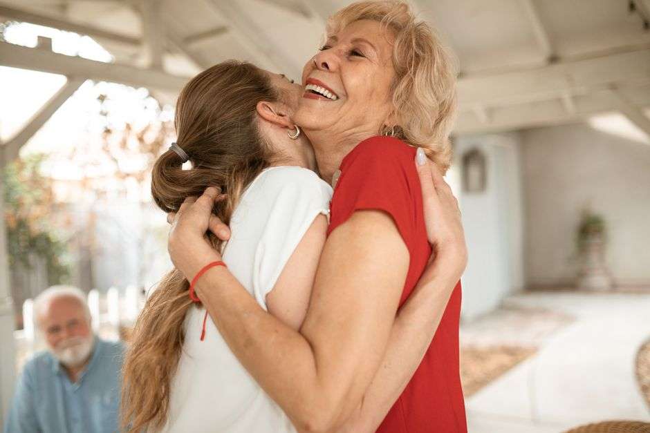Two women share a joyful embrace, reflecting a family reunion