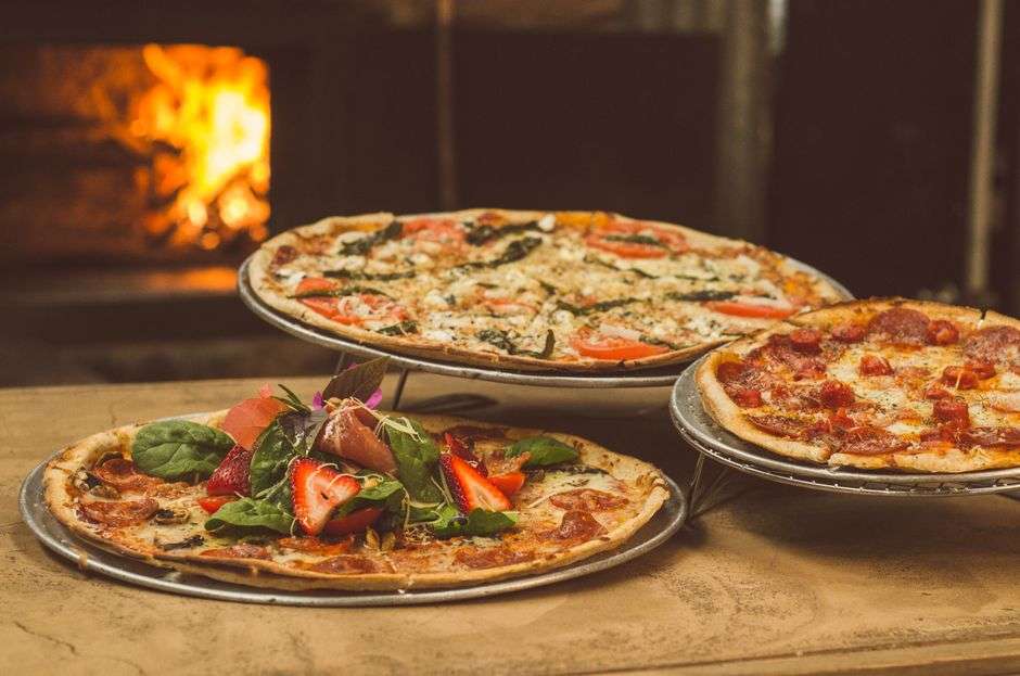 Wood-fired pizzas topped with fresh ingredients at a neighborhood pizza pub