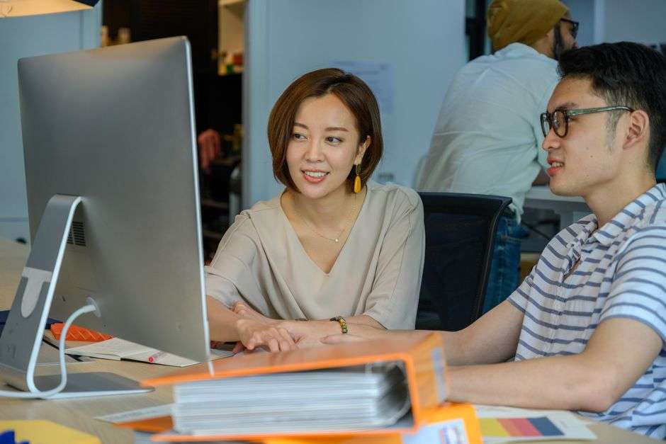 Two young adults collaborate at a desk during a workplace internship