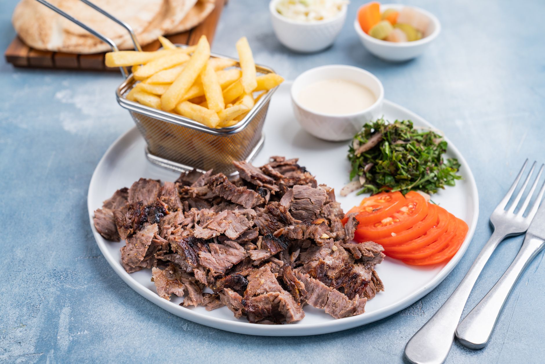 A plate of Mediterranean food with hummus and grilled meat