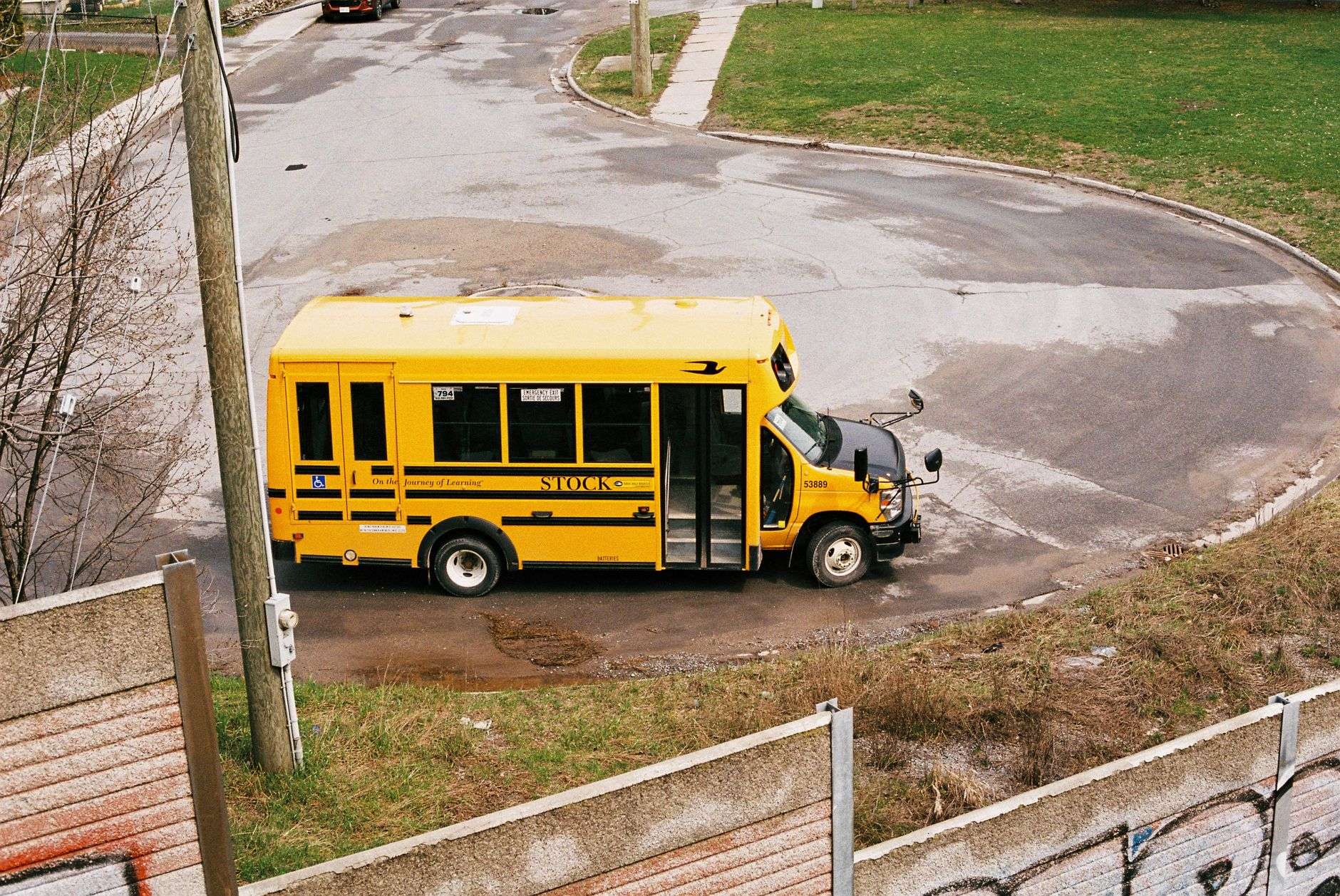 A yellow school bus stopped on a residential road with its lights on