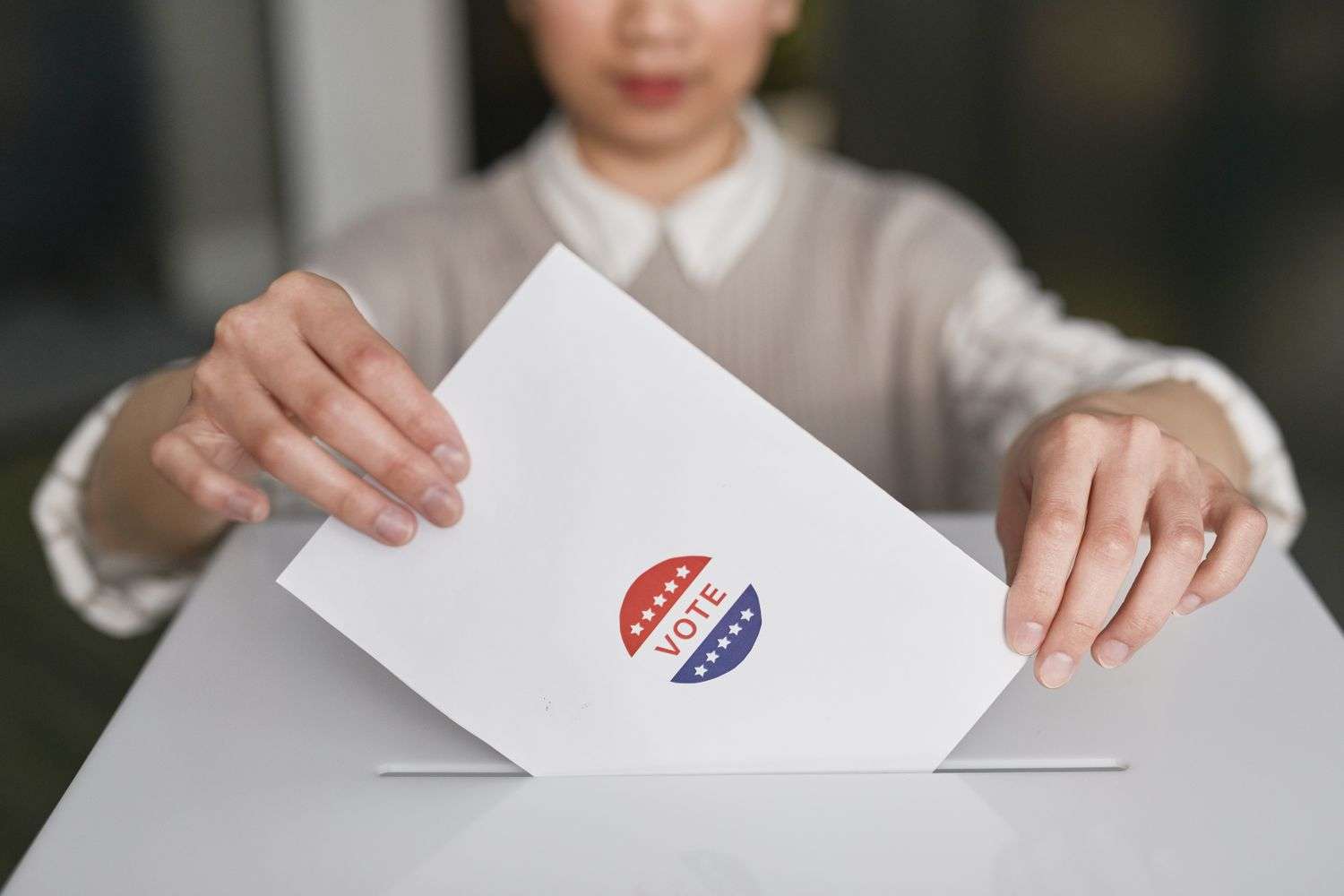 A voter placing a completed paper ballot into a ballot box