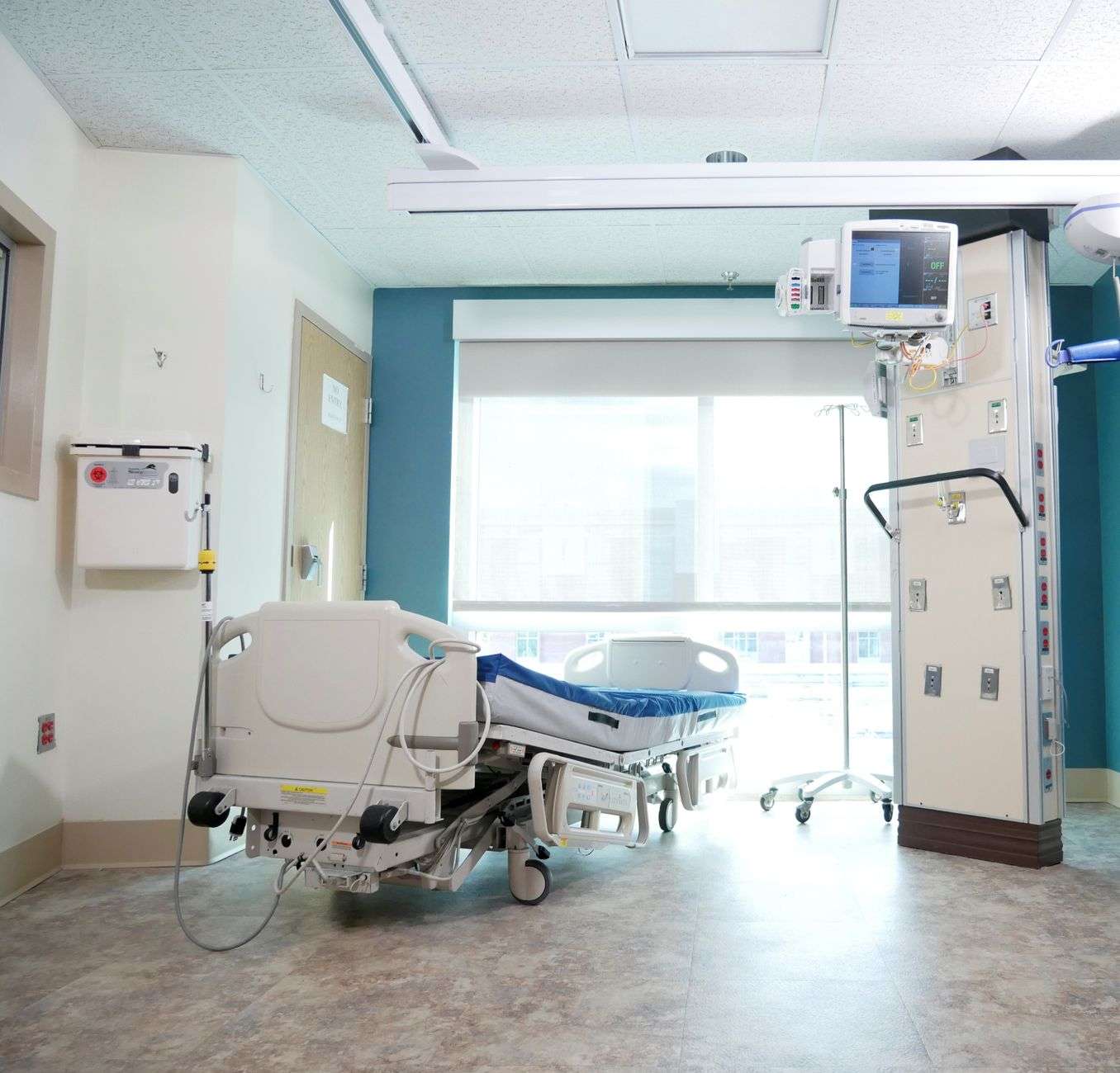 A hospital intensive care unit with advanced life-support equipment beside a patient bed.