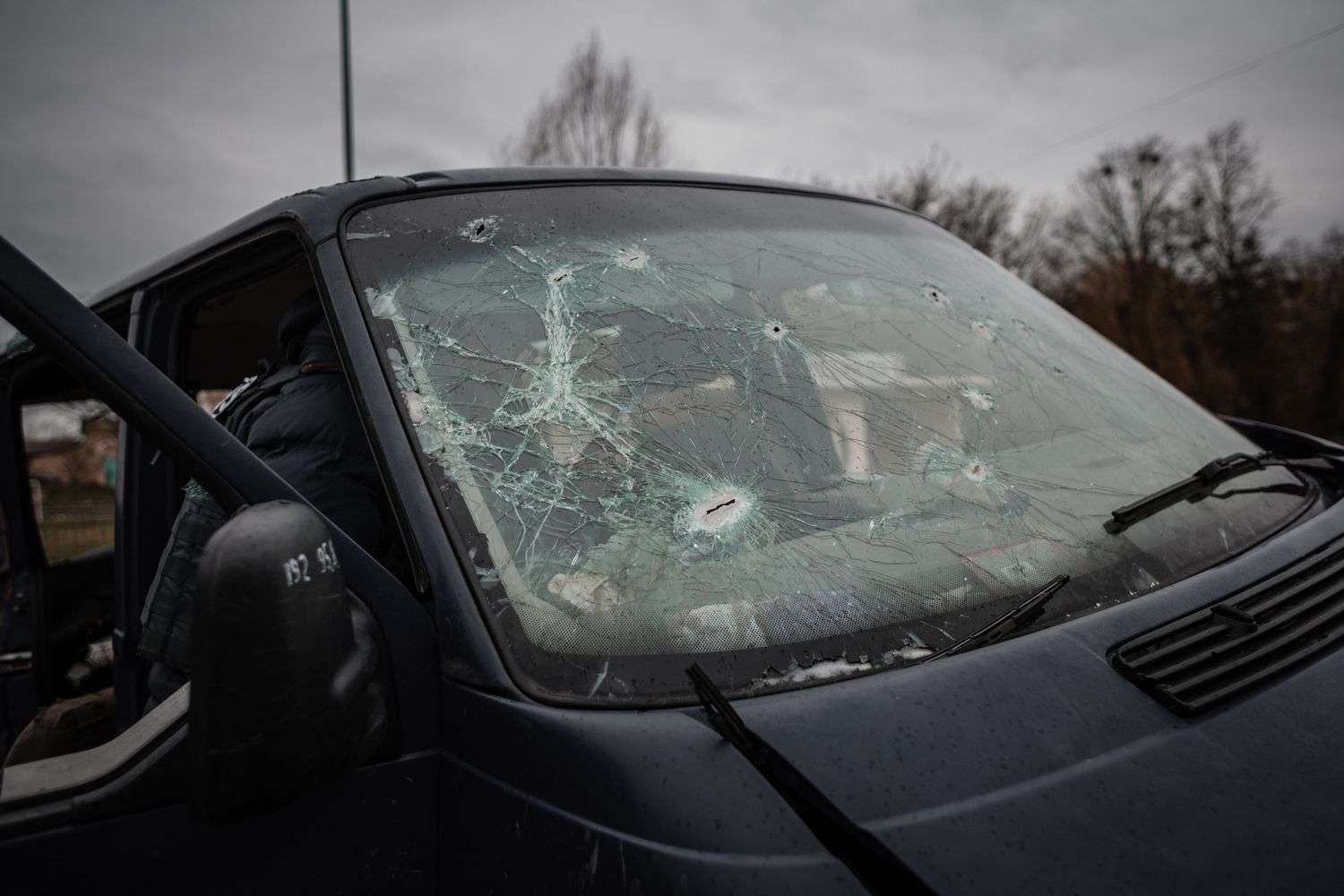 Shattered glass visible inside a truck with a bullet-damaged window