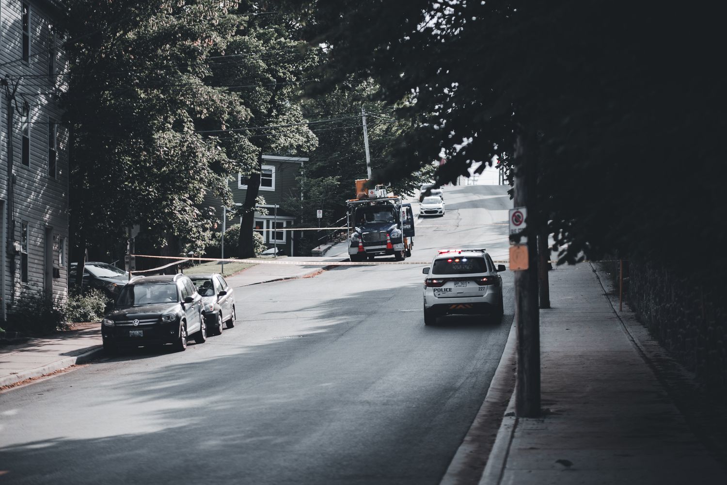 A police car parked along a residential street as officers investigate