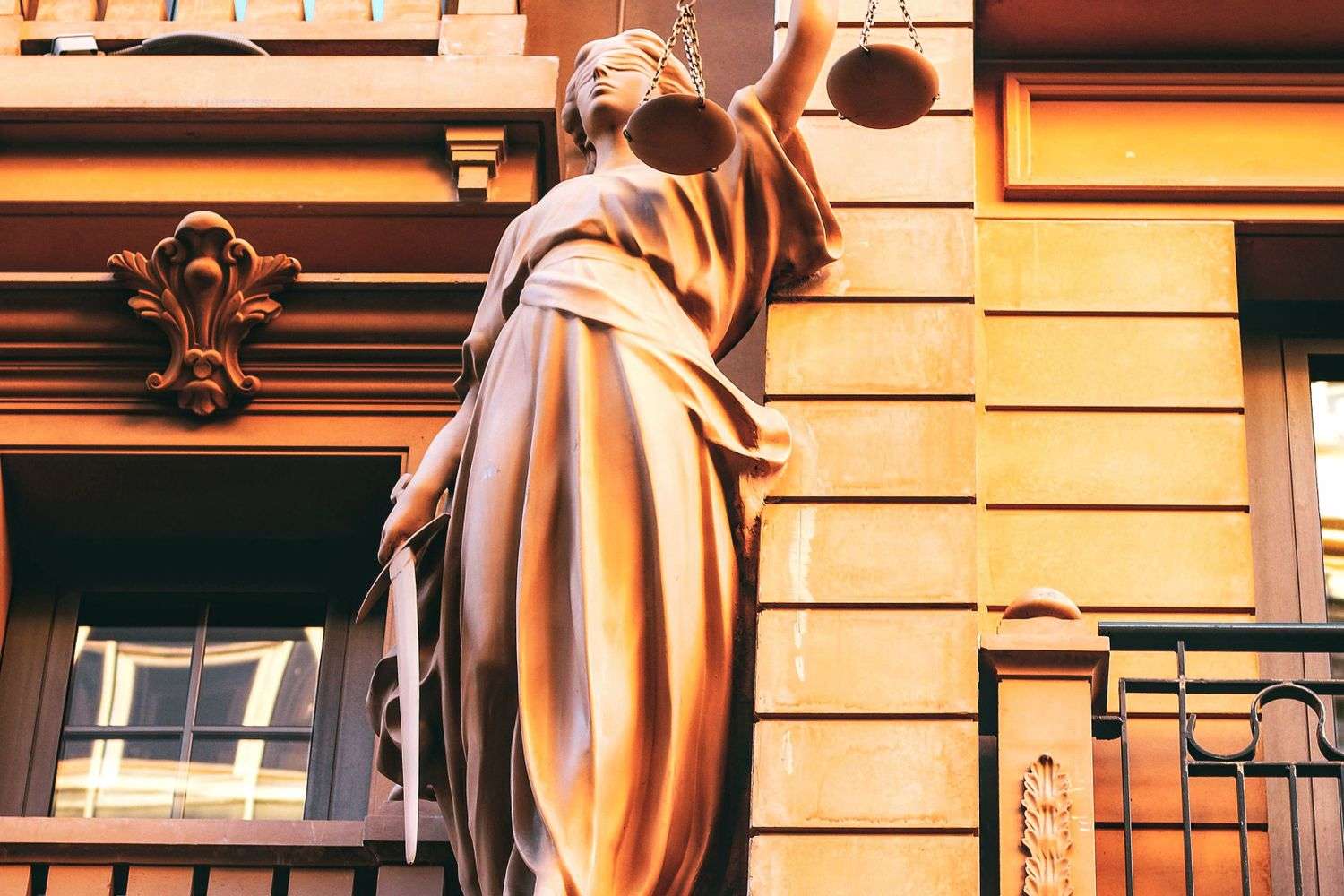 A bronze statue of the scales of justice outside a courthouse