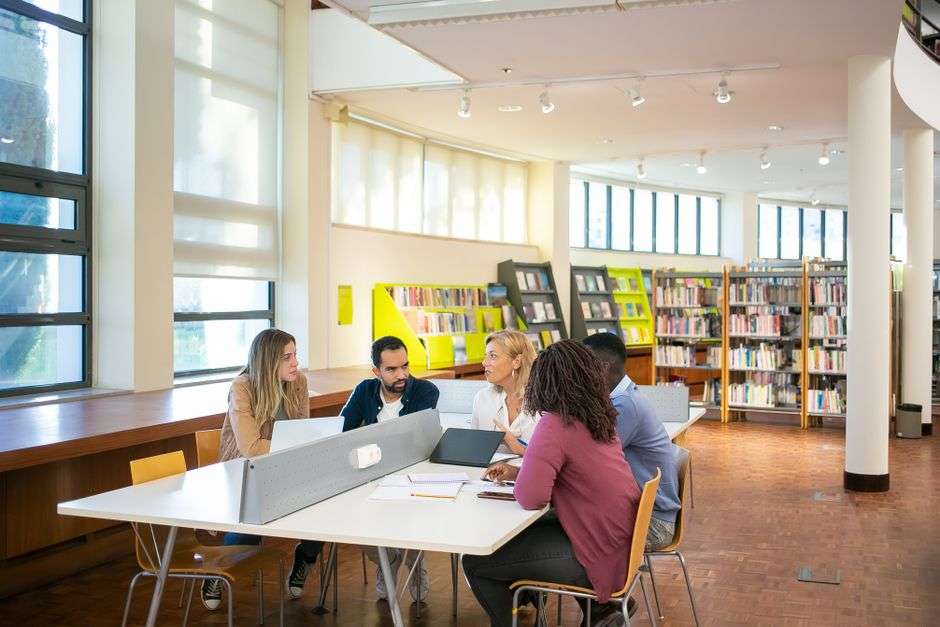 Students working together at a table in a bright, modern collaborative campus space