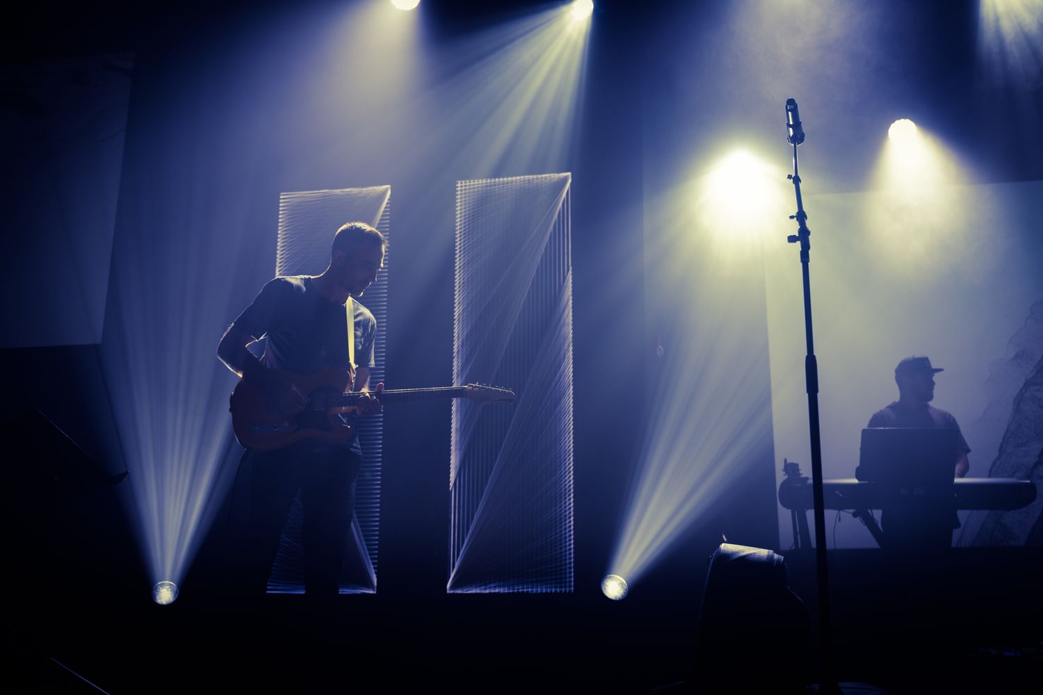 Musicians perform a live concert under colorful lights at an intimate club