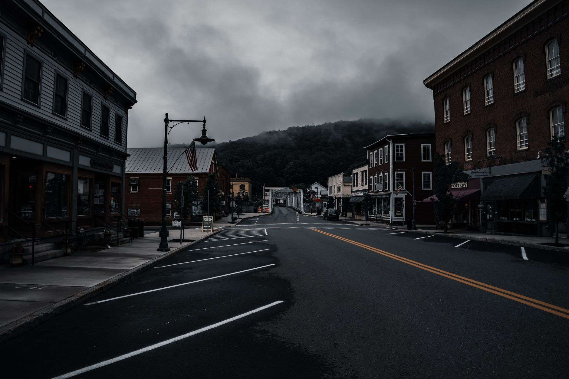 An empty small-town street lined with historic buildings under a cloudy sky.