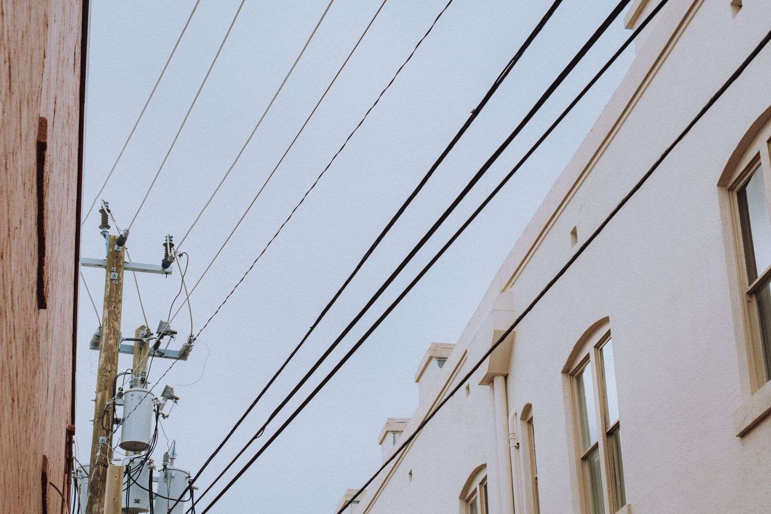 Power lines and utility poles along a road near a school building