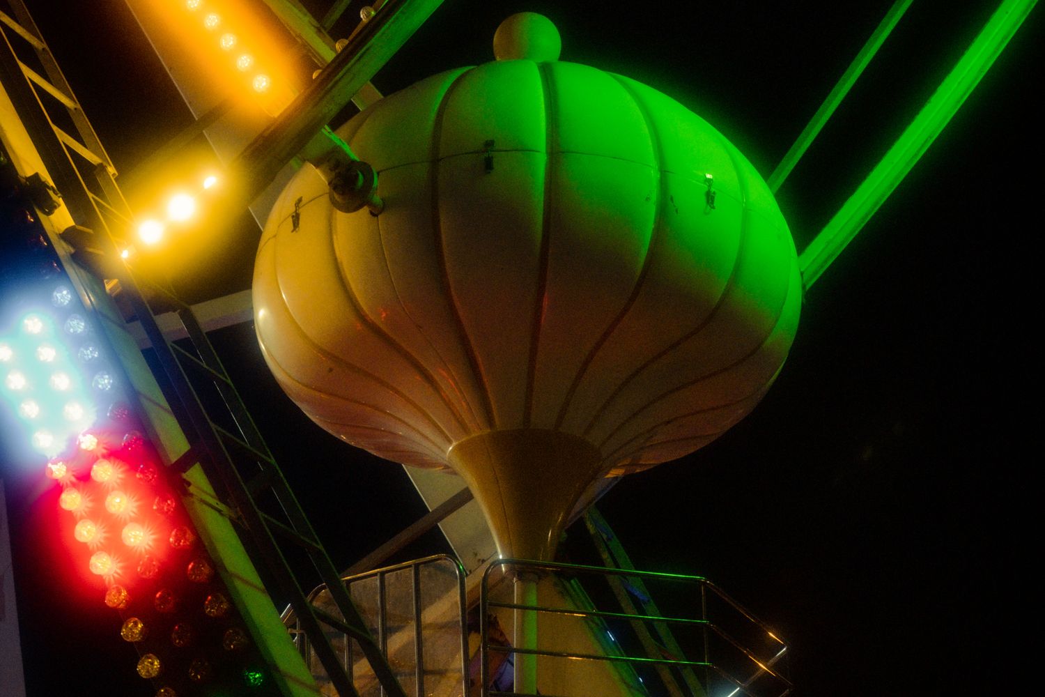 A ferris wheel lit with colorful lights at a fairground after dark
