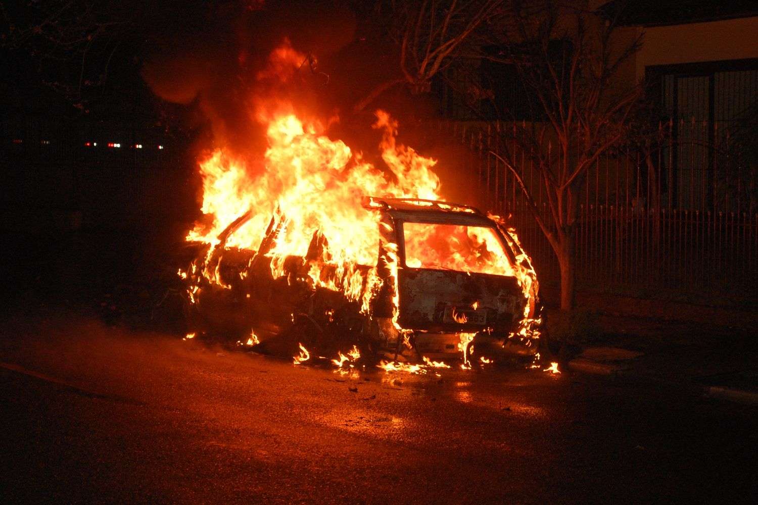 Burning car with flames and smoke at a fuel station