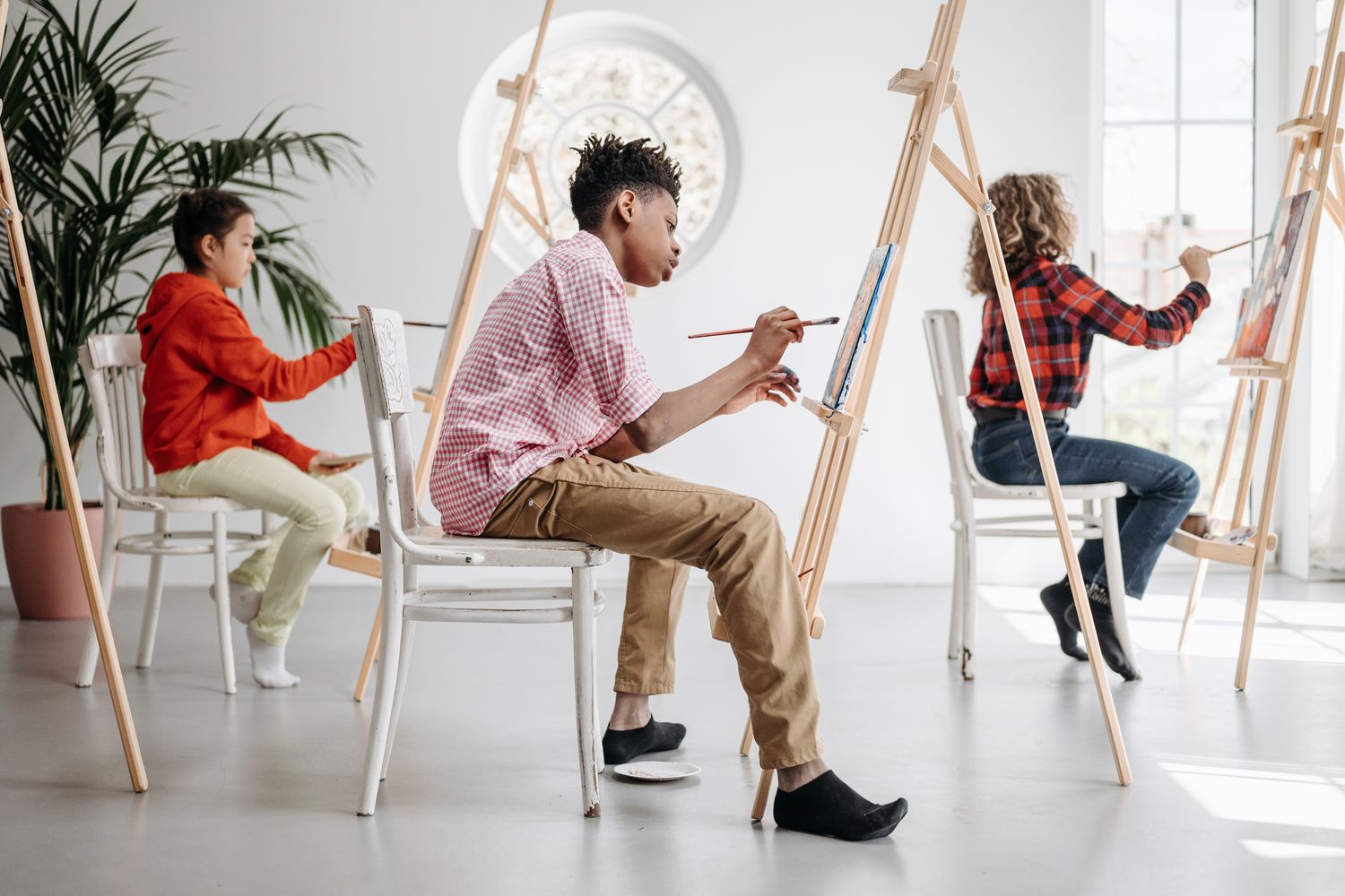 Students of all ages creating artwork together in a bright community art studio