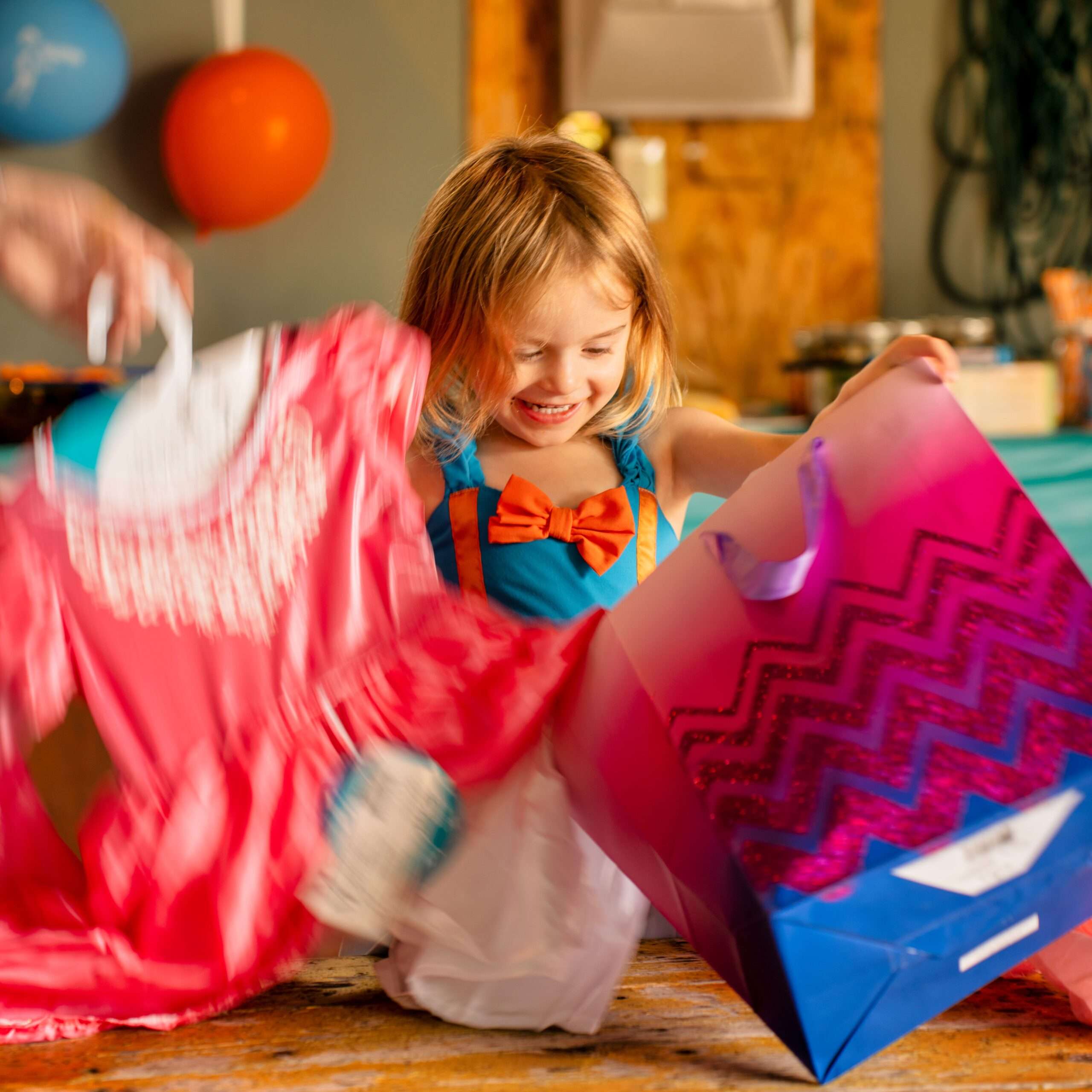 A joyful child opens a colorful gift bag surrounded by party decorations