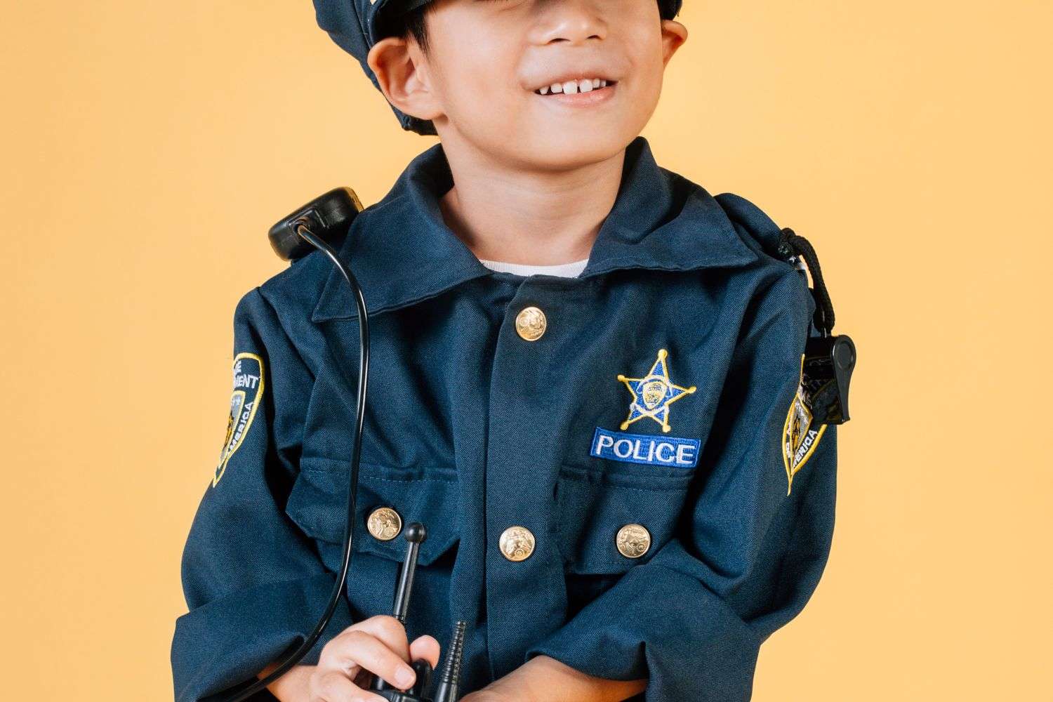 A young child dressed in a toy police officer costume, smiling