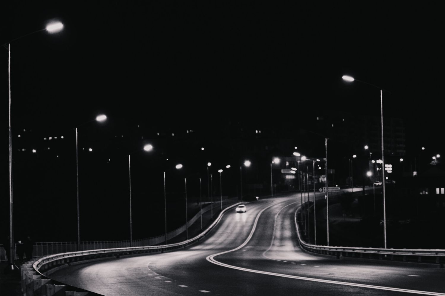 Empty roadway lit by streetlights after dark