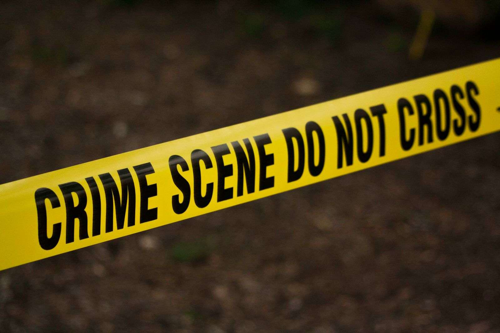 Crime scene tape and numbered evidence markers at a murder investigation scene in Mobile