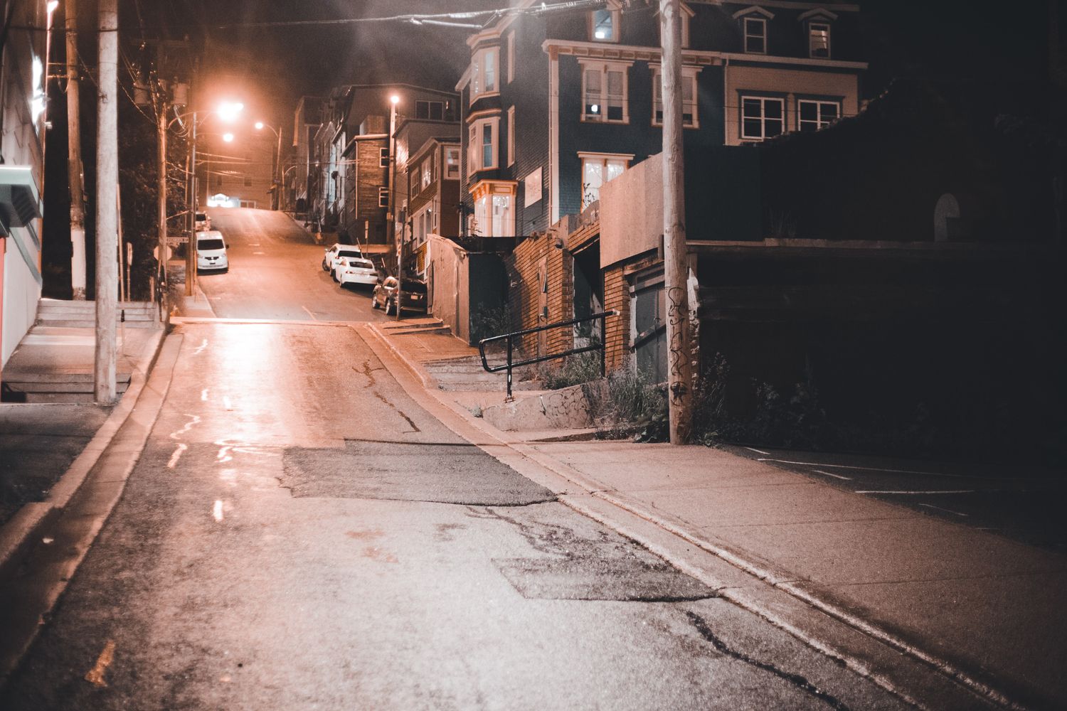 An empty residential street in Mobile at night lit by streetlights
