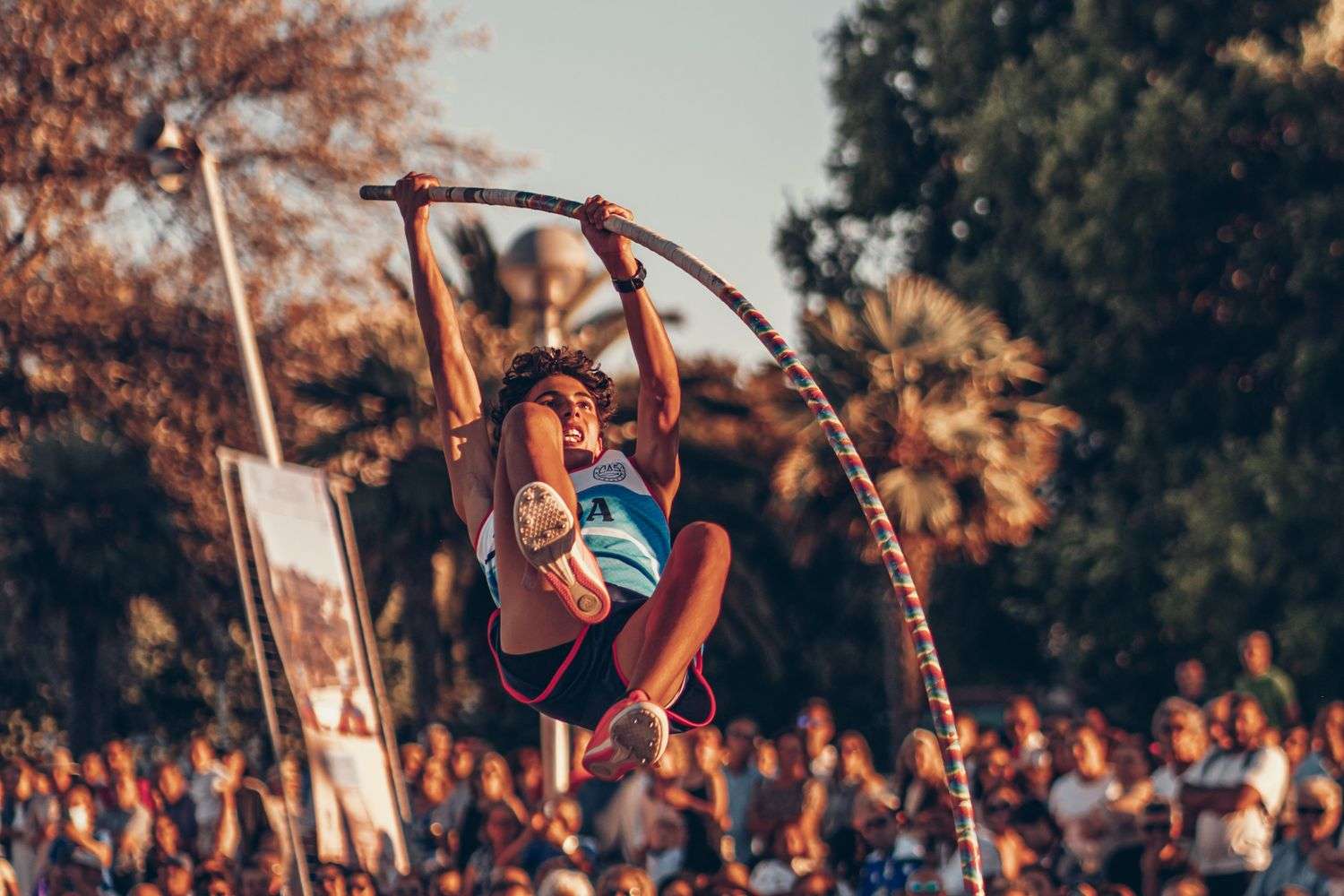 A pole vaulter clears the bar at an outdoor event