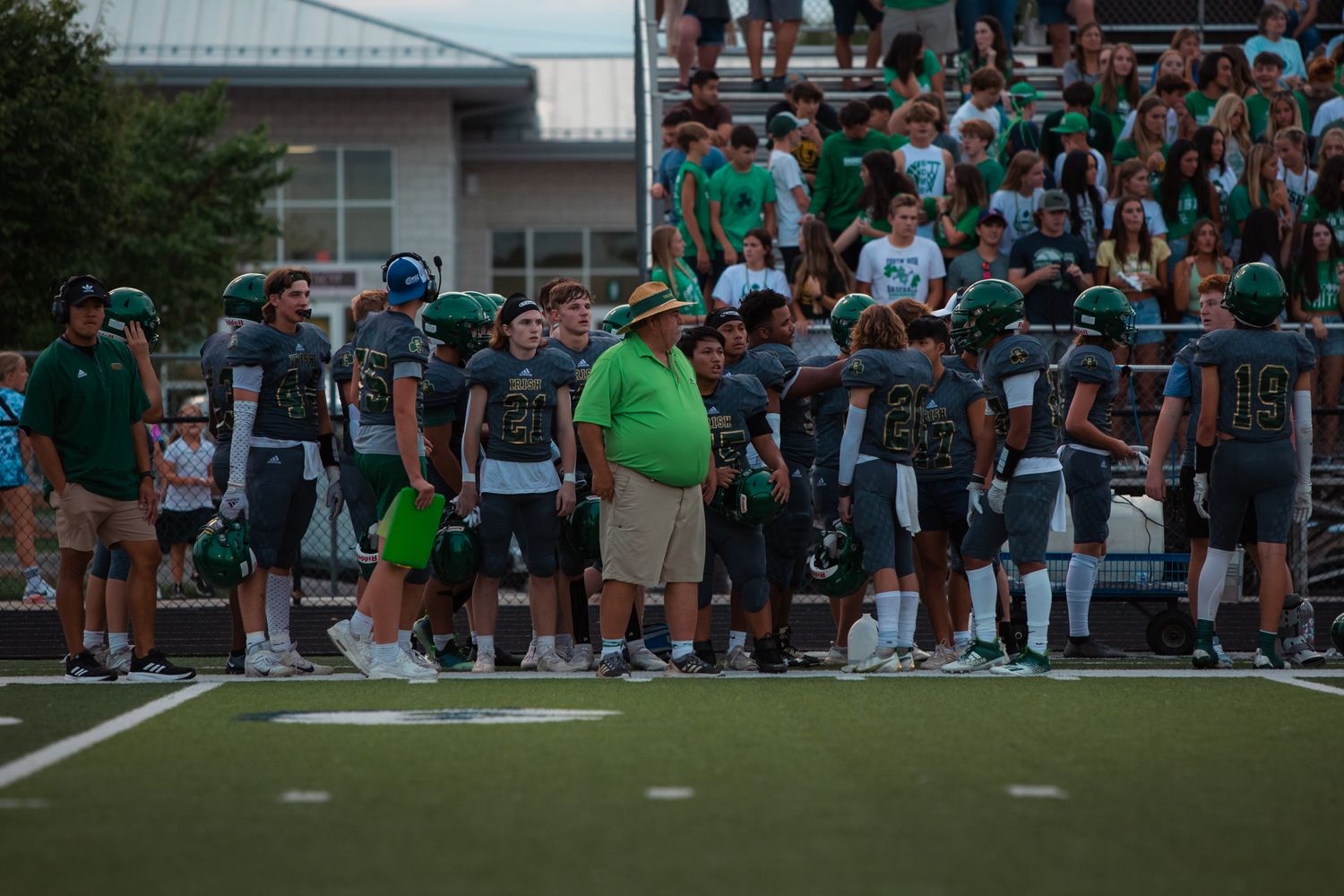 A head football coach watching from the sideline during a high school game
