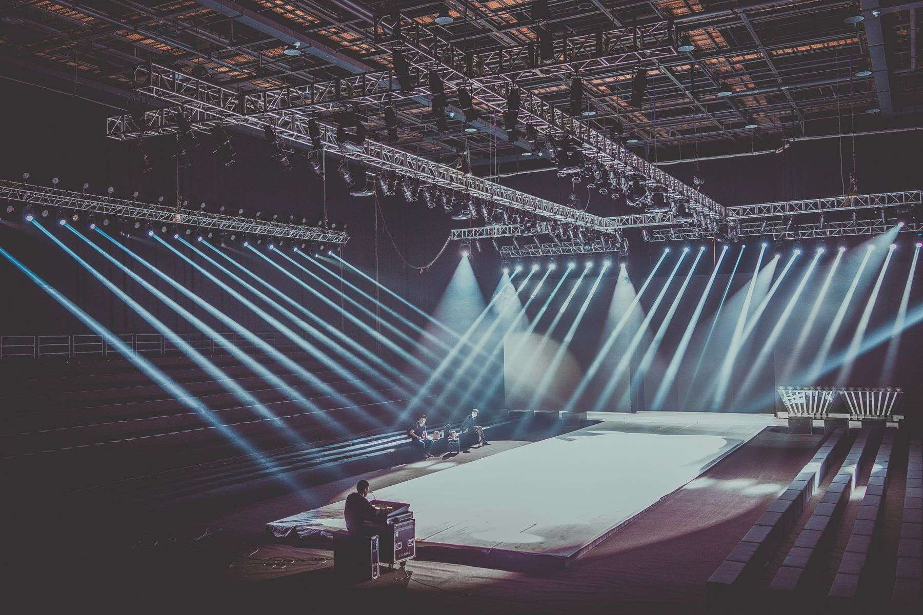 Spotlight beams illuminate an empty stage before an evening program