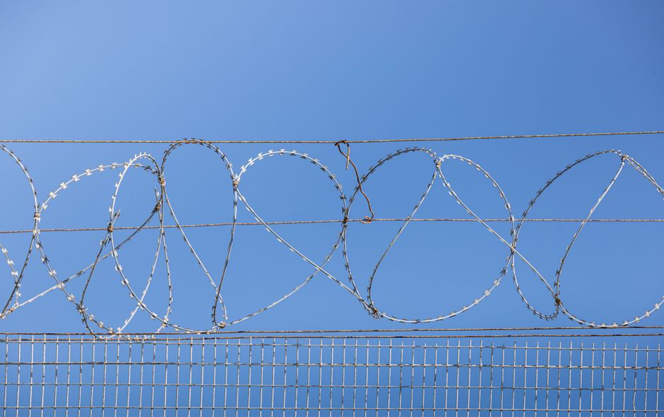 Tall security fence with razor wire outside a correctional facility