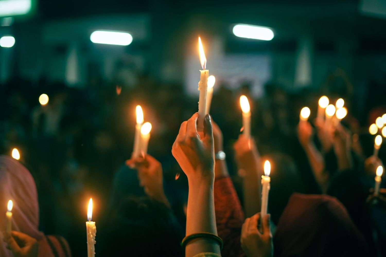 Crowd holding candles at an evening vigil for two missing fishermen