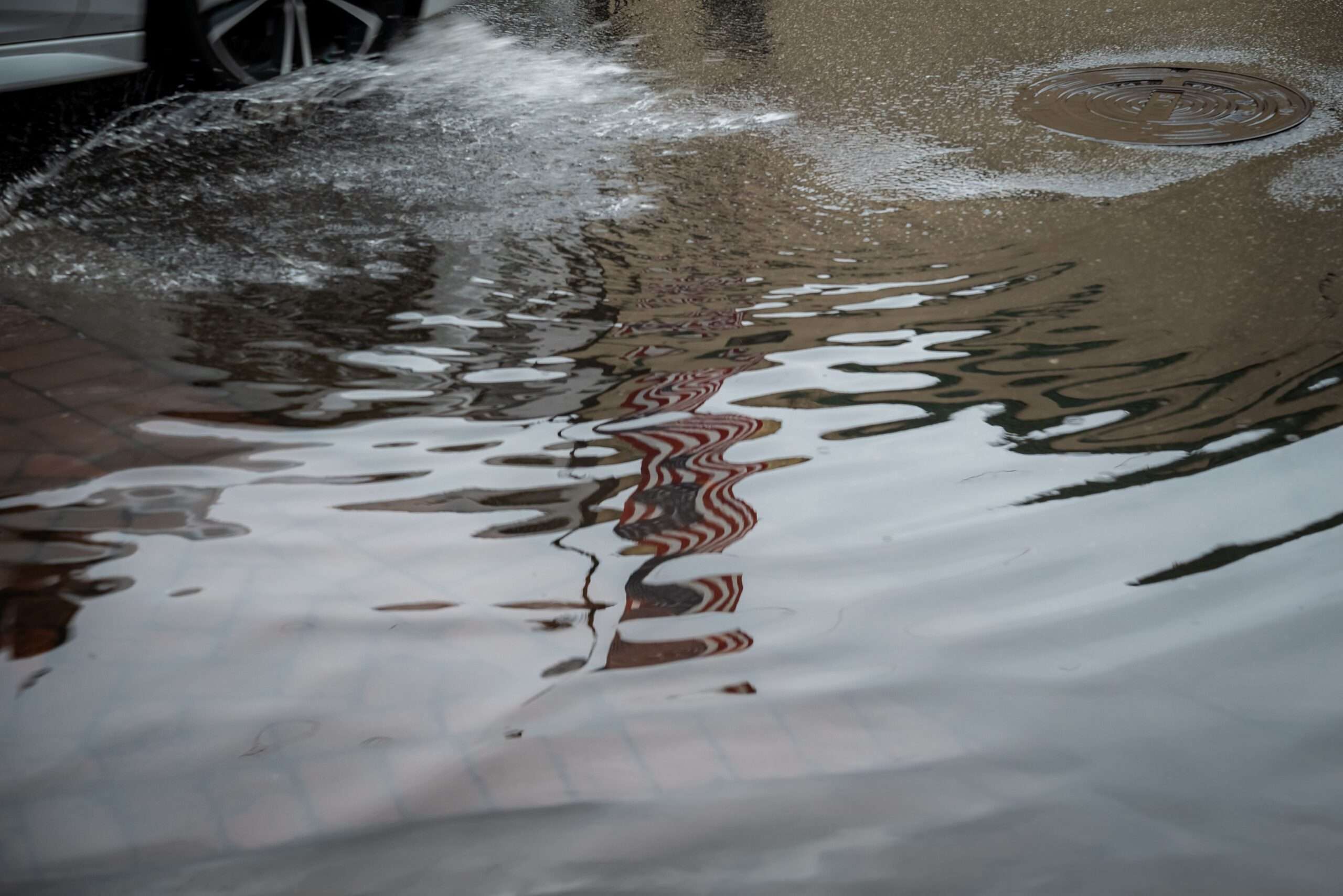 A flooded urban street reflecting buildings after heavy rainfall