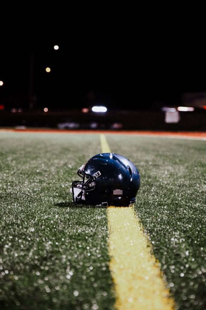 A football helmet resting on the field under stadium lights at night