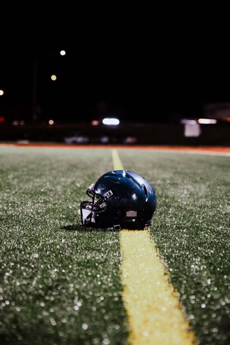 A football helmet resting on the field under stadium lights at night
