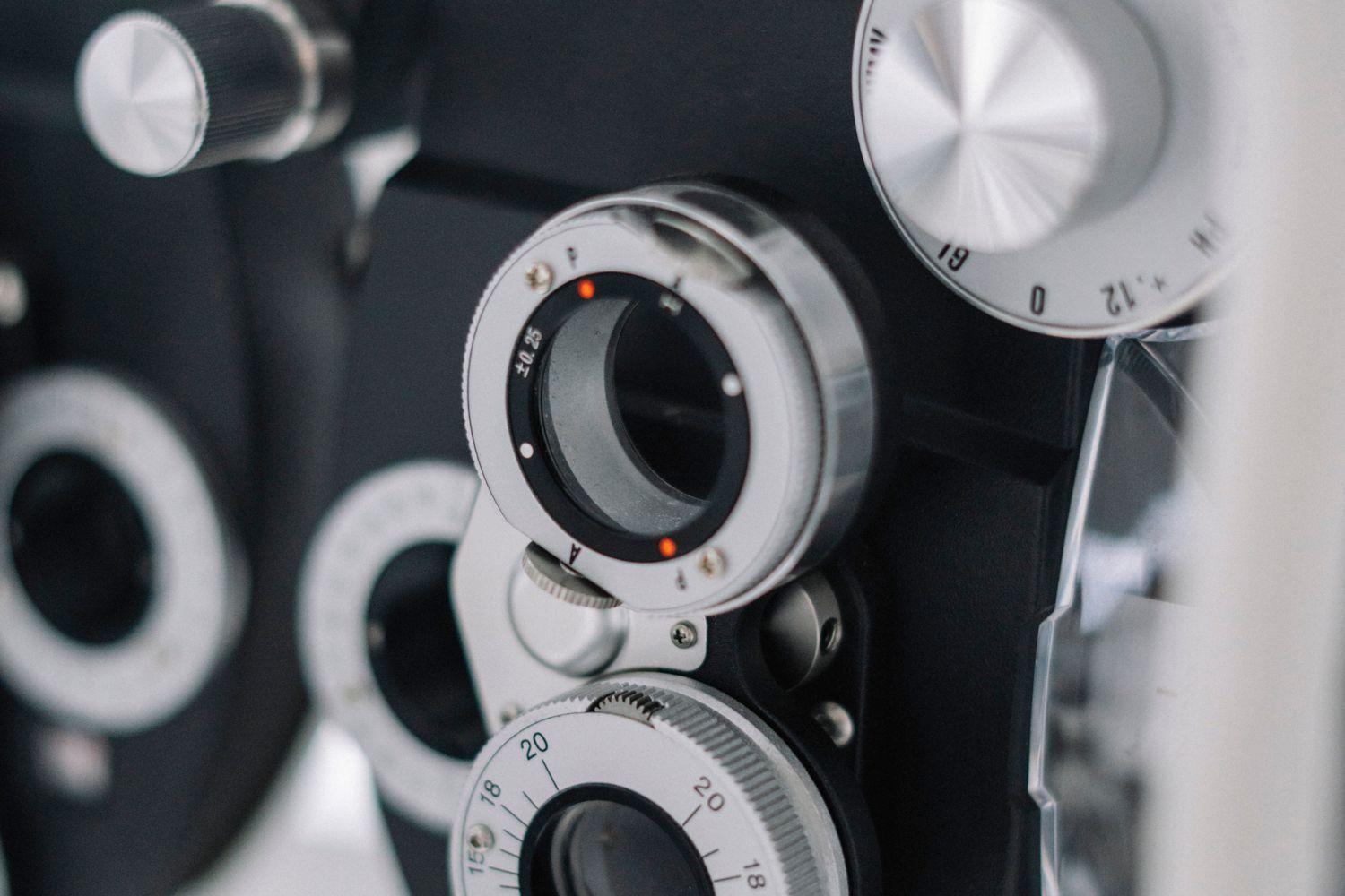 Eye doctor examining a patient's eyes with testing equipment in an exam room