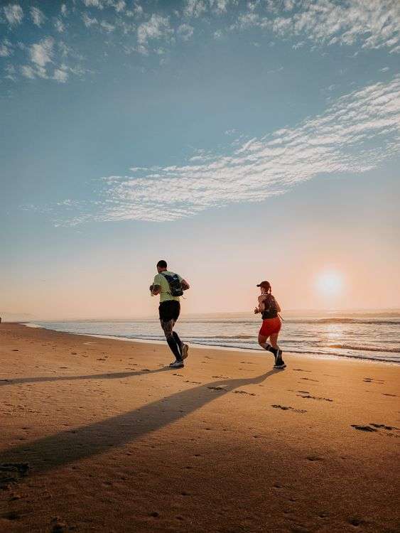 Two runners jogging along a sandy Gulf Coast beach at sunrise