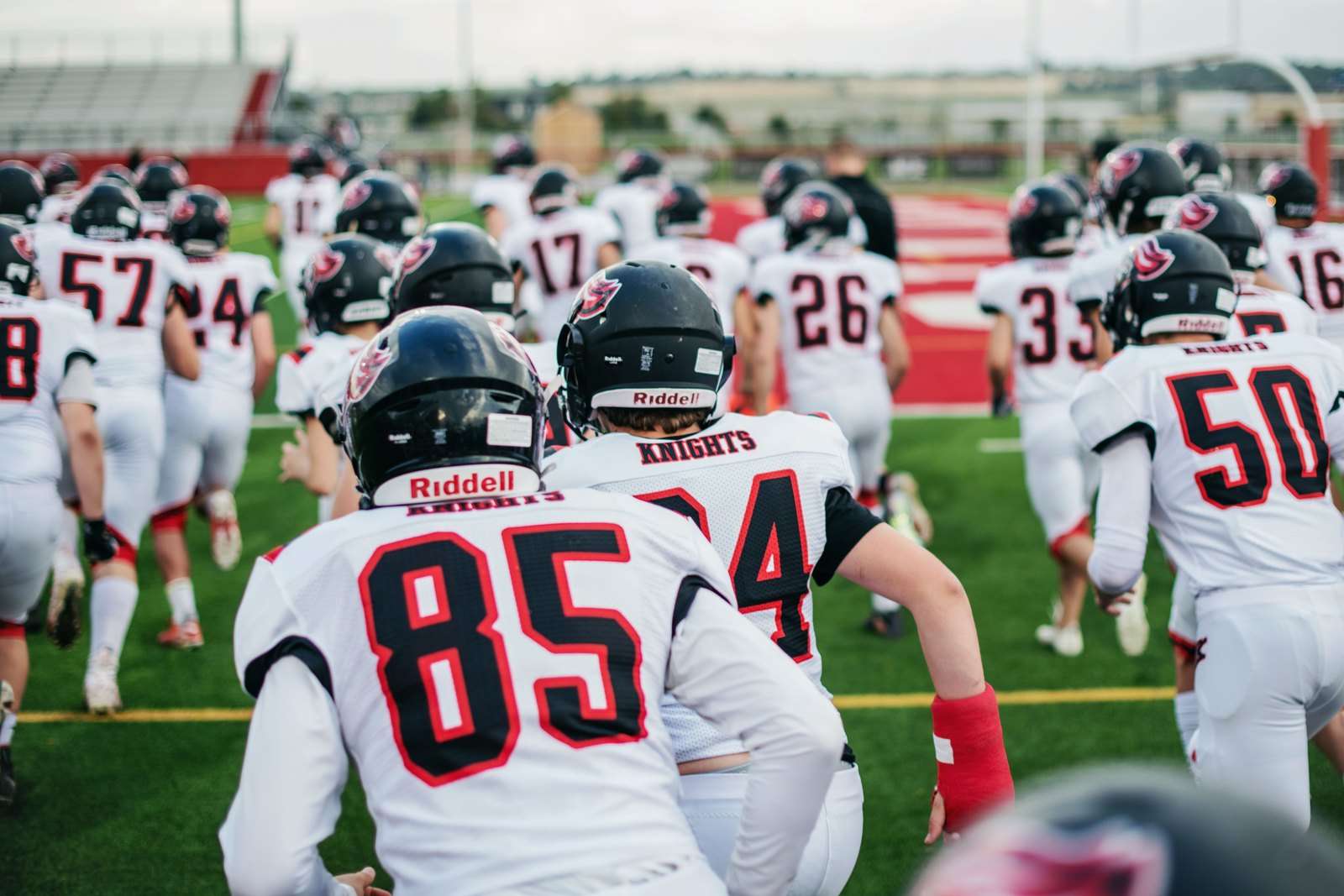 High school football players in uniform running onto the field before a game