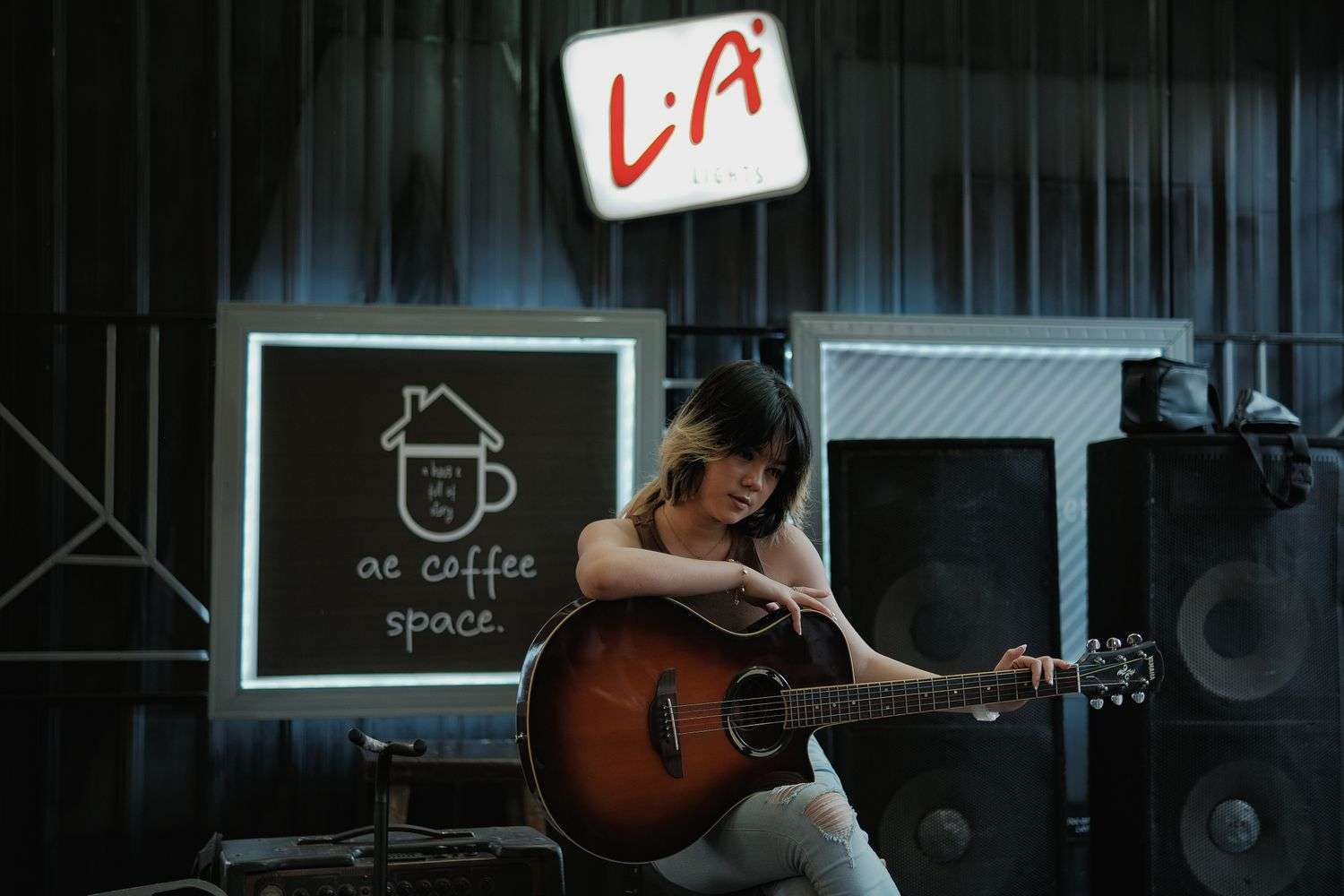 A singer-songwriter performing with a guitar in a coffee house listening room