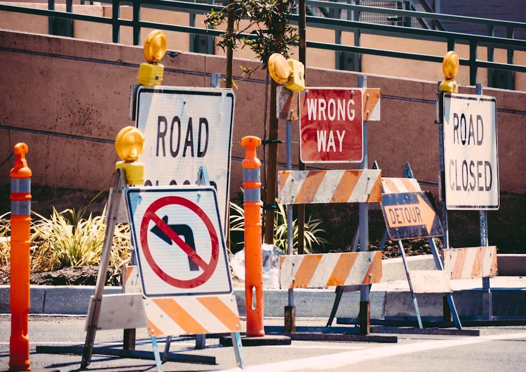 Orange road closed, wrong way, and detour signs alongside traffic cones and barricades at a road construction zone