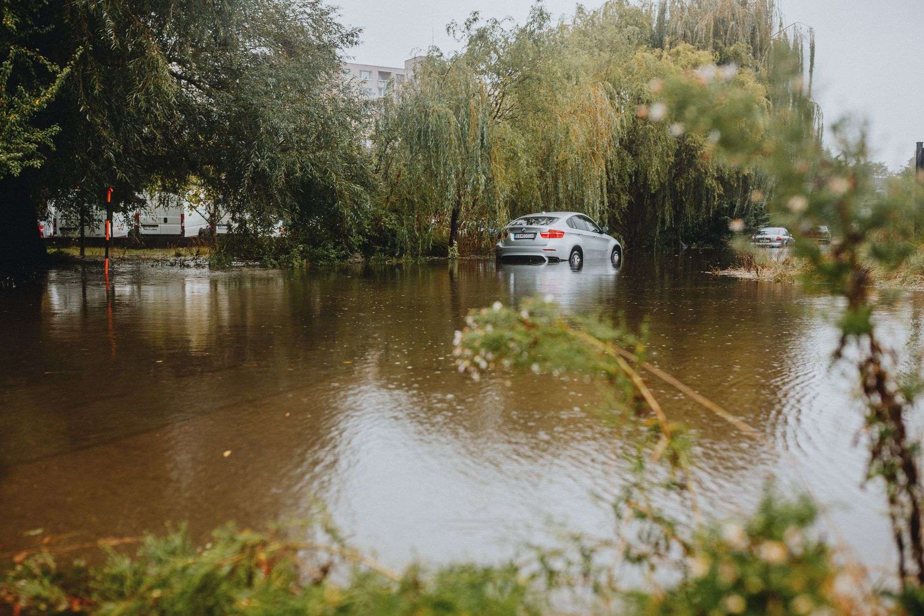 Flooded street in Northwest Florida with a vehicle driving through standing water after heavy storms