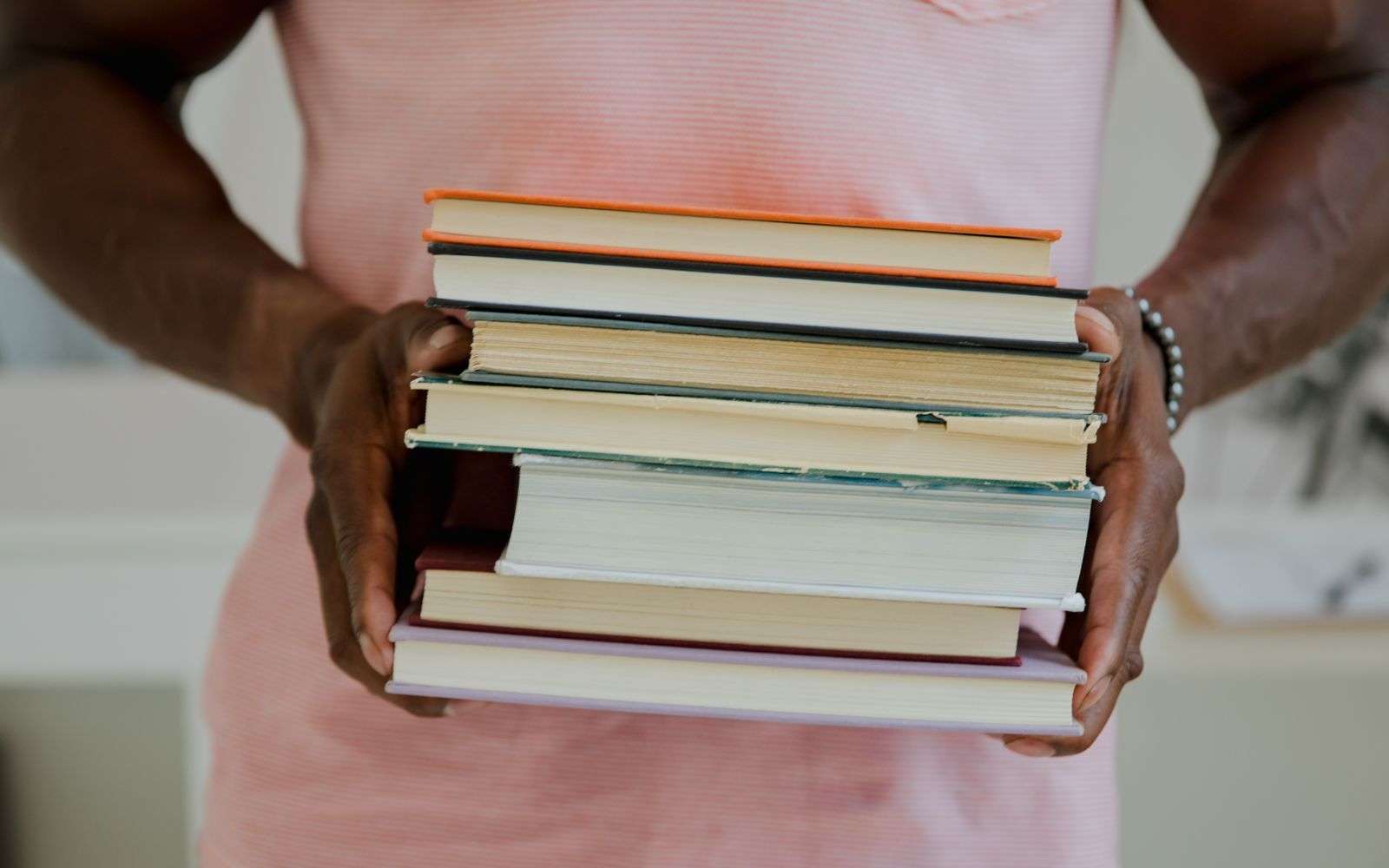 Close-up of a persons hands holding a stack of books