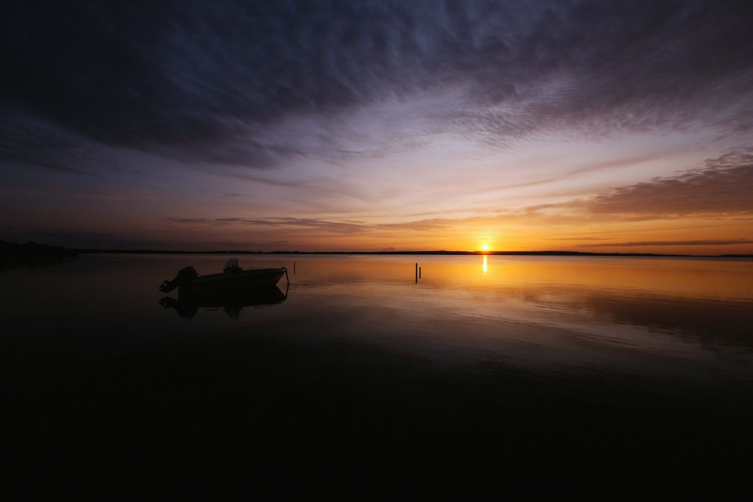 Small boat anchored on calm water at sunset