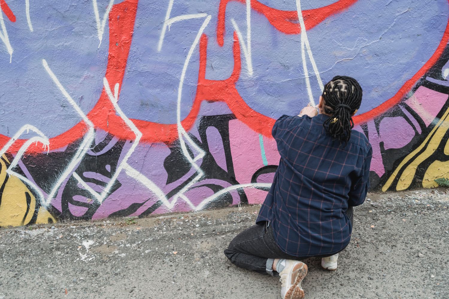 Artist at work painting a vibrant mural during a Mobile community art event