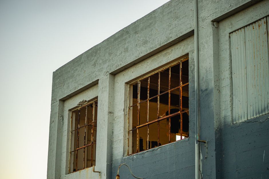 A boarded-up, dilapidated commercial building with broken windows