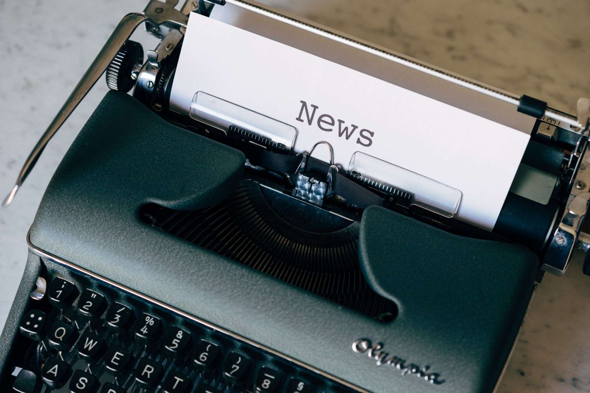 A vintage typewriter with a sheet of paper reading News, symbolizing journalism
