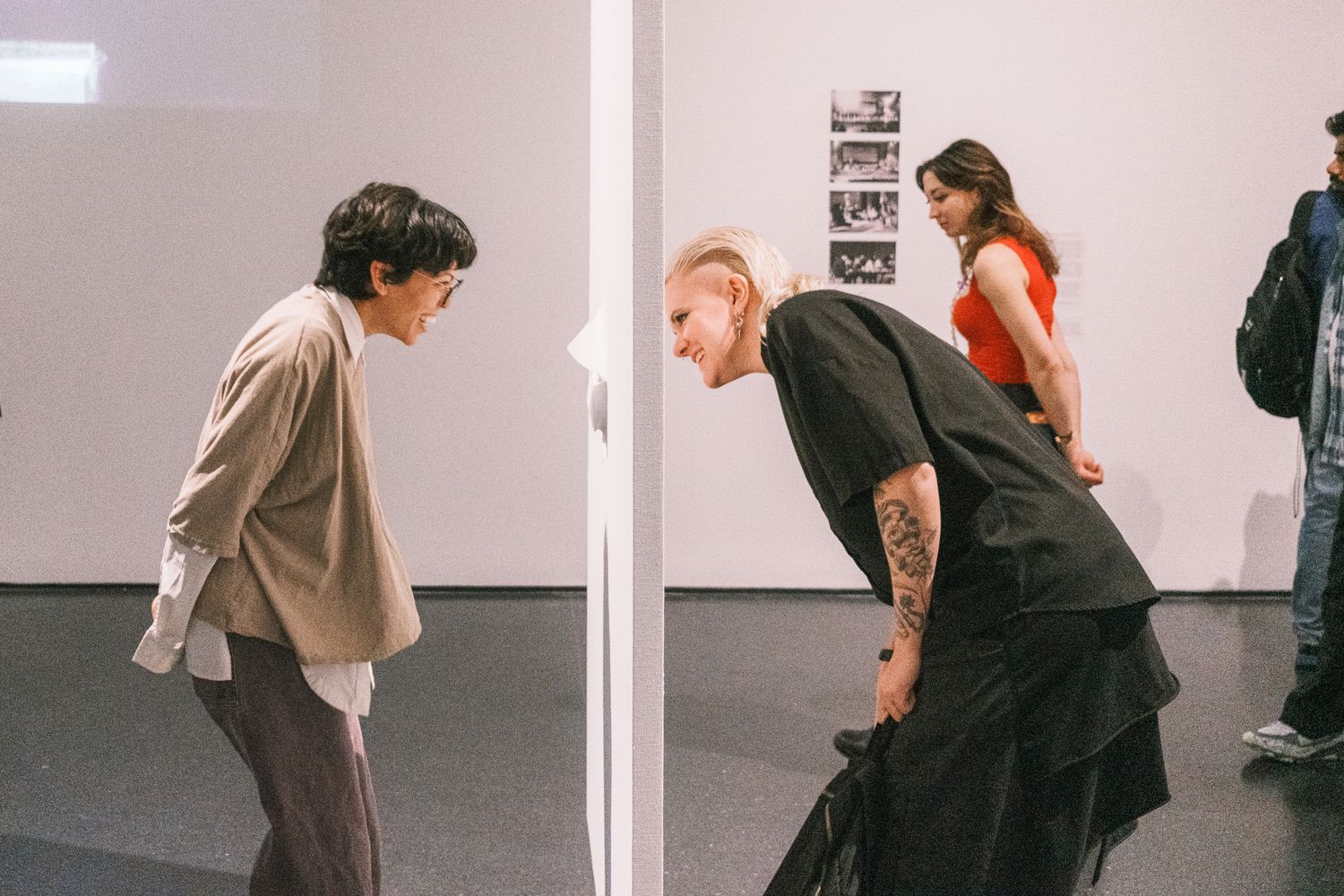 Visitors admire artwork hanging on the walls of a bright gallery