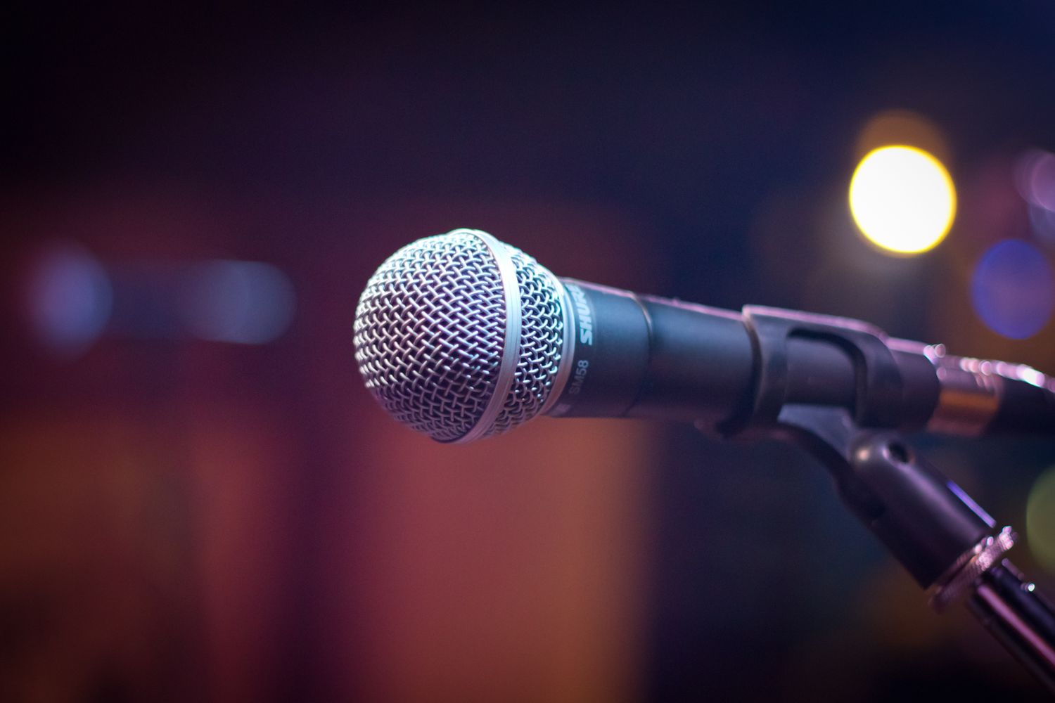 A microphone standing in a broadcast studio under warm lighting
