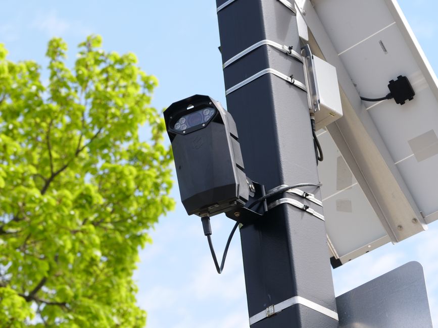 A security camera mounted on a pole above a city street