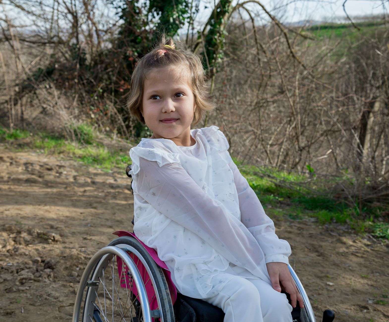 A child using a wheelchair with a caregiver, representing families affected by Medicaid waiver reviews