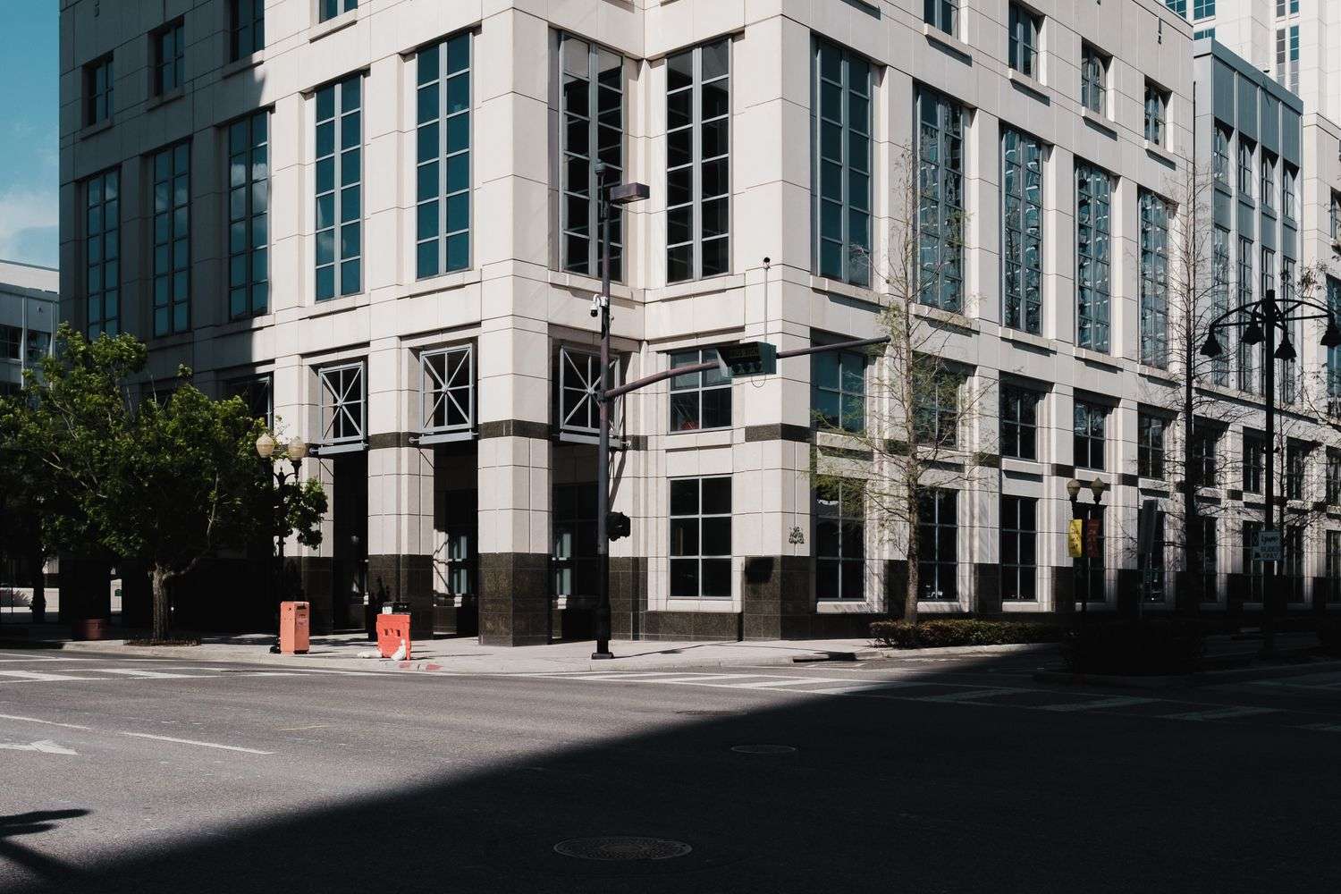 Modern multi-story building at a downtown street corner with trees and streetlights