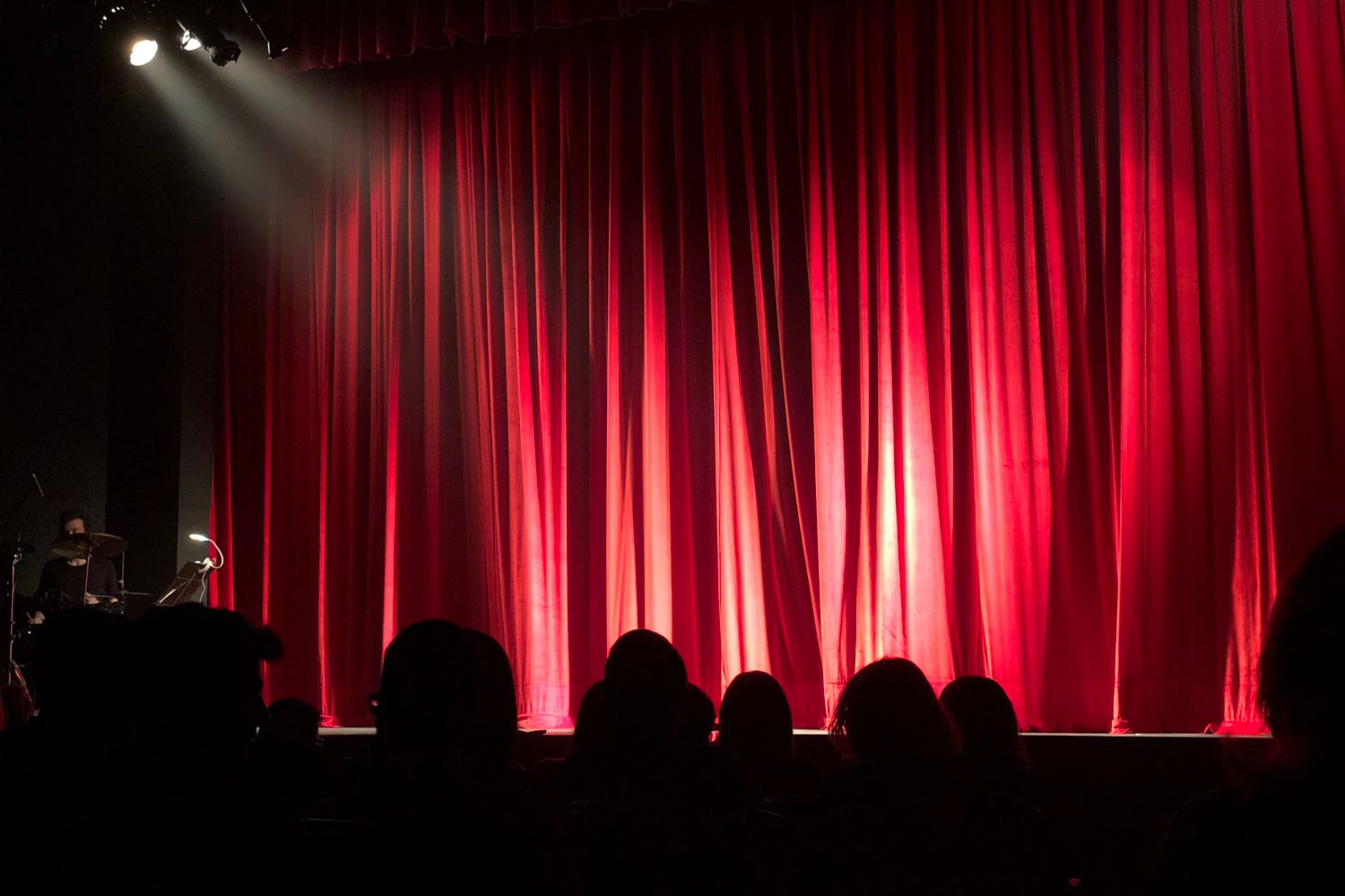 A performer stands under a spotlight on a theater stage during a festival show